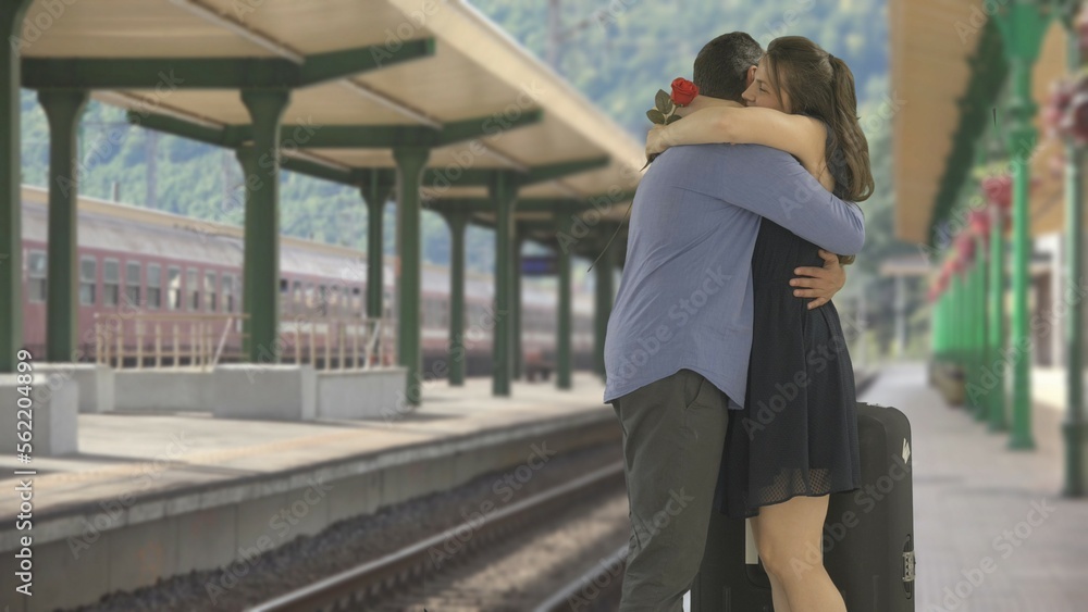 Man give red flower to woman, couple meet and embrace in train station