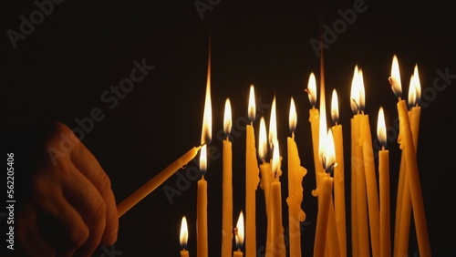 Detail of hand taking holding a candle take light from other candle, sharing