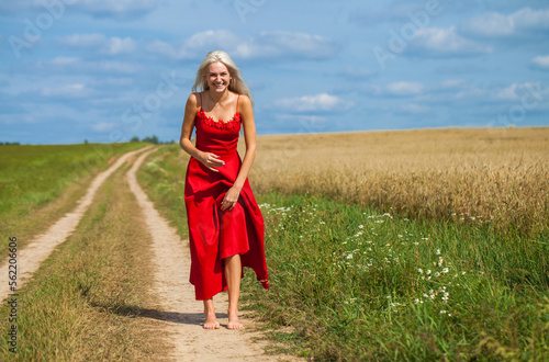 young woman in a red dress posing in a wheat field