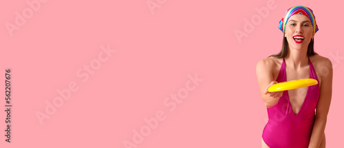 Beautiful young woman playing frisbee on pink background with space for text