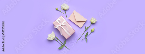 Gift box, envelope and beautiful flowers on lilac background