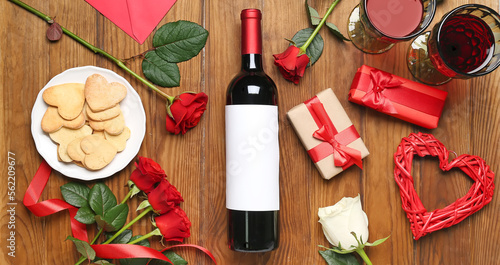 Composition with bottle of wine, rose flowers, cookies and gifts on wooden background. Valentine's Day celebration
