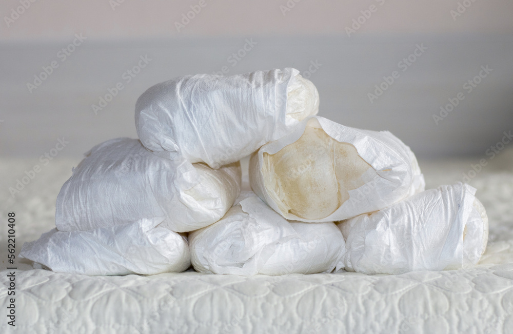 Obraz premium stack some many used disposable baby diapers isolated on gray carpet floor or bed in small trash bin can conceptual photography.toddler infant newborn diaper in pyramid or chaotic thrown down