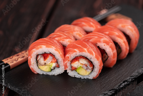 Sushi roll maguro with tuna, smoked eel, avocado, philadelphia cheese on black board close-up. Sushi menu. Japanese food.