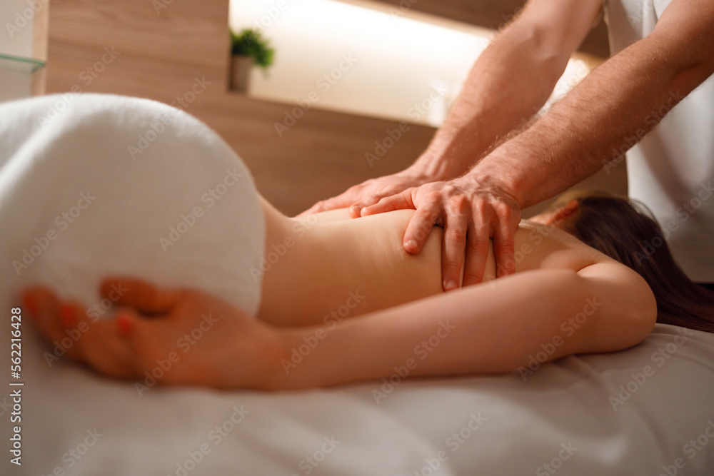Young woman getting a back massage from male masseur at spa Young woman getting a back massage from male masseur at spa
