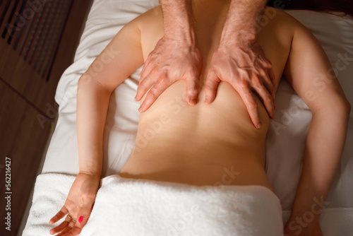 Professional masseur makes a therapeutic massage of the woman s back