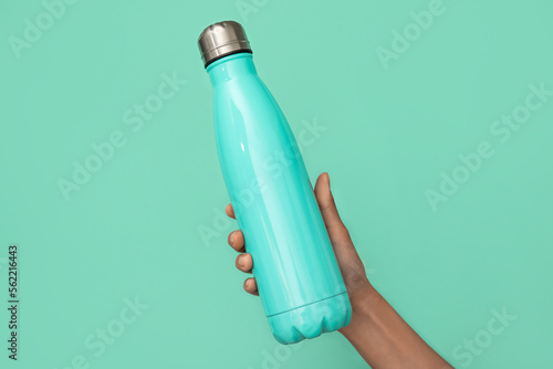 Female hand with sports water bottle of water on color background