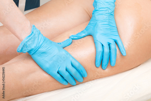 Close-up of a cosmetologist hands in blue gloves doing buttocks massage. © Nobilior