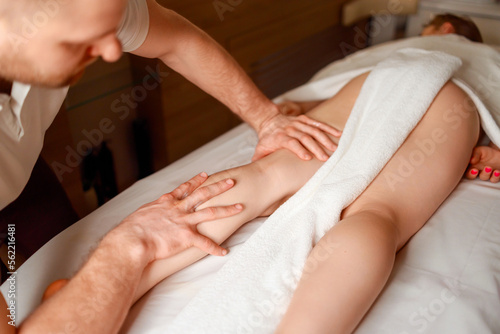 Masseur massaging woman's leg in spa salon
