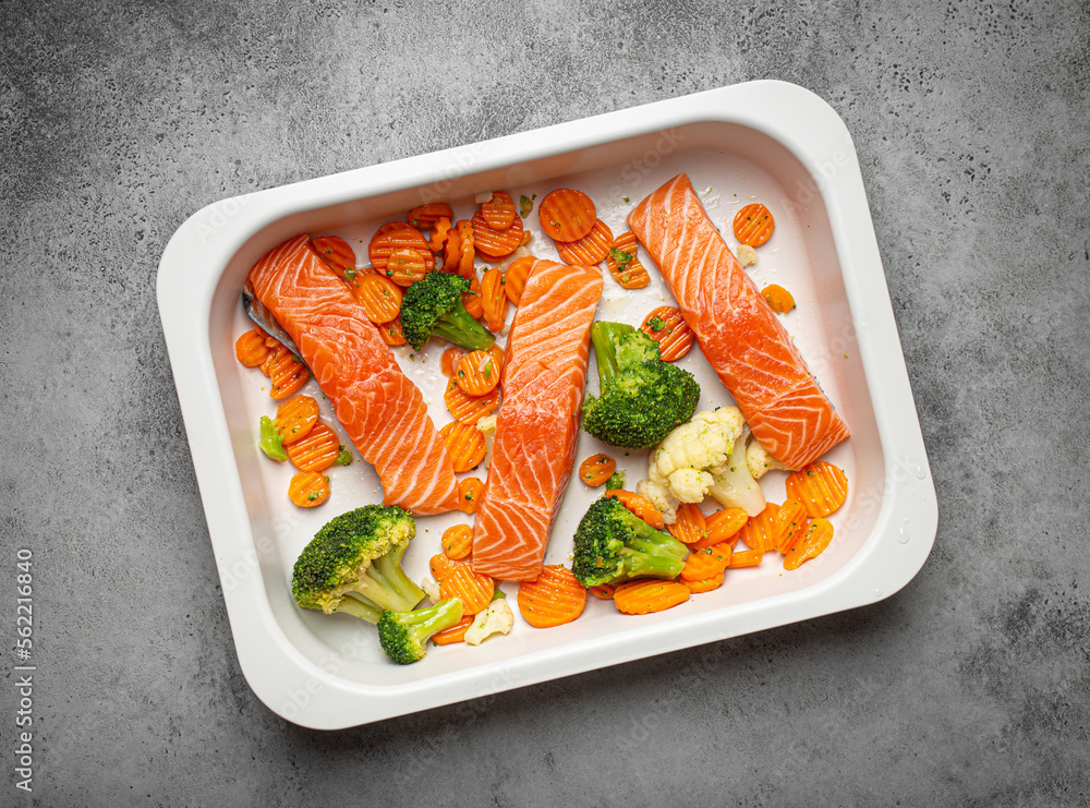 Top view of baking dish casserole with raw uncooked fish salmon steaks, broccoli, cauliflower, carrot. Preparing a healthy low carb dinner concept Top view of baking dish casserole with raw uncooked fish salmon steaks, broccoli, cauliflower, carrot. Preparing a healthy low carb dinner concept
