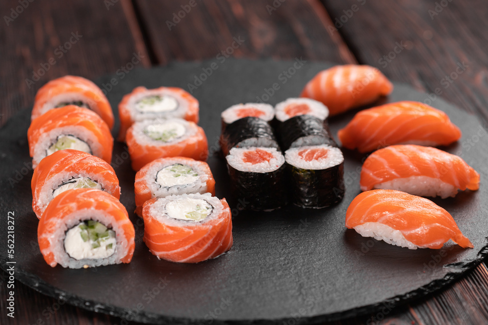Sushi set from top on black background close-up. An assortment of various maki nigiri and rolls seafood soy sauce Sushi set from top on black background close-up. An assortment of various maki nigiri and rolls seafood soy sauce