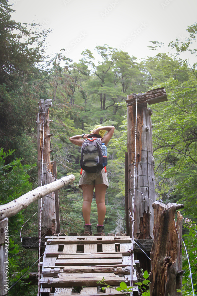 young woman prepares to cross a bridge in the forest young woman prepares to cross a bridge in the forest