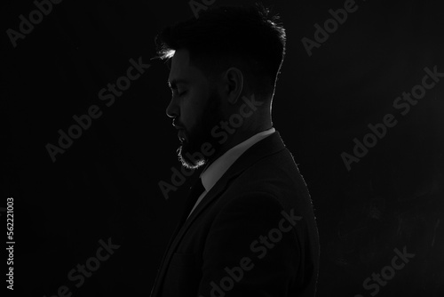 Silhouette of young man in suit on dark background, closeup