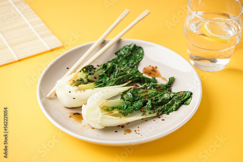 Plate of tasty stewed pak choi cabbage with soy sauce on yellow background