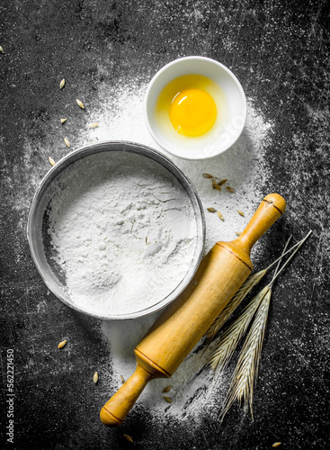 Flour in a sieve with a rolling pin and spikelets.