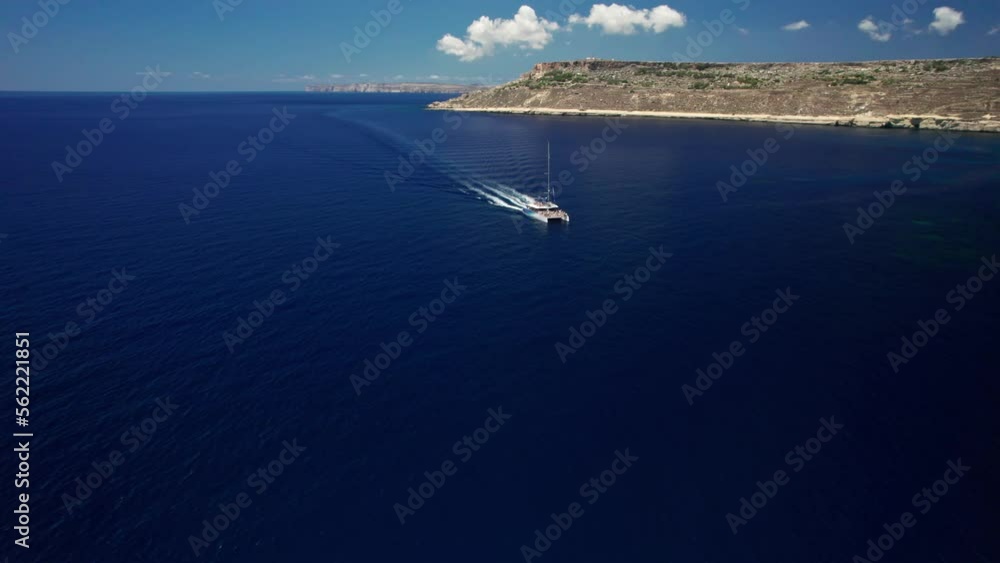 4K aerial top view of a boat floating on the blue water of the sea. People on a sunny day relax, sunbathe, have fun on a yacht. The boat is approaching the drone. Nature of Malta, Europe filmed in 4k. 4K aerial top view of a boat floating on the blue water of the sea. People on a sunny day relax, sunbathe, have fun on a yacht. The boat is approaching the drone. Nature of Malta, Europe filmed in 4k.