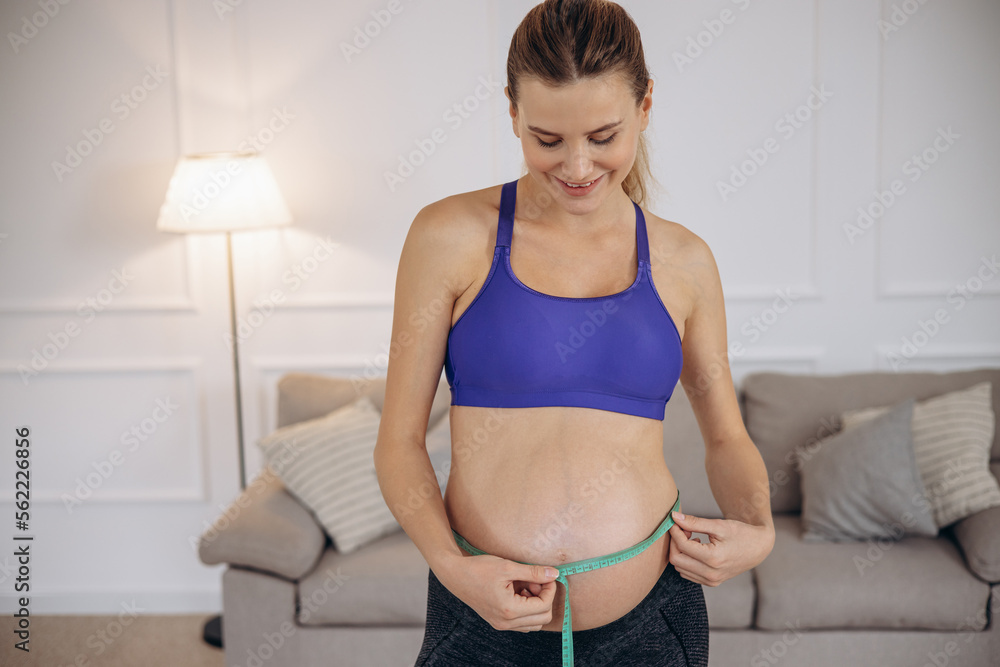 Pregnant woman measuring belly with measuring tape