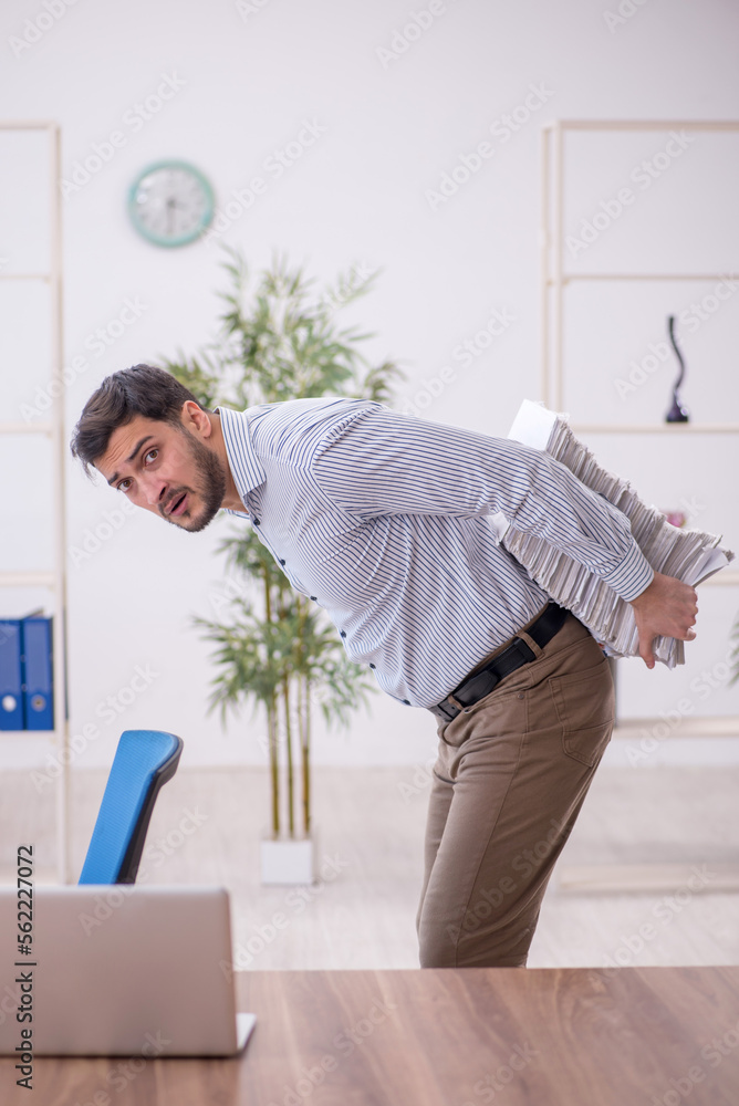 Young male employee and too much work in the office Young male employee and too much work in the office