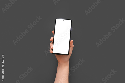 Female hand with modern mobile phone on grey background, closeup