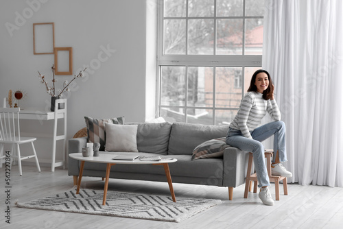 Young woman sitting on grey couch in living room