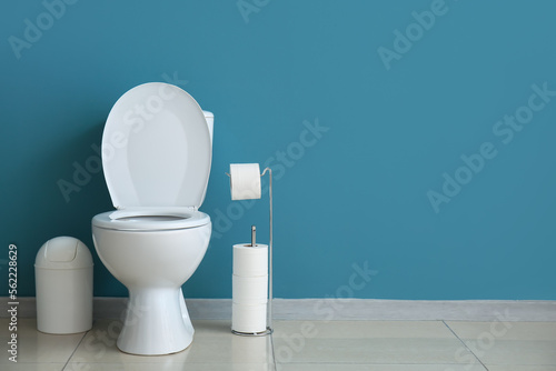 Photos Ceramic toilet bowl, bin and paper rolls near blue wall
