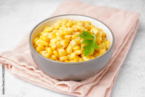 Bowl with canned corn kernels, parsley leaf and napkin on white background