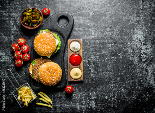 Burgers with fries,tomatoes and jalapenos in bowl .