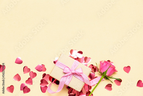 Beautiful composition with gift box, confetti and rose flower on color background. Valentine's Day celebration