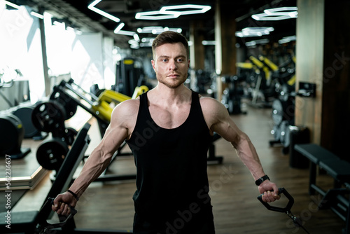 Young athletic man in gym training. Handsome bodybuilder working out.
