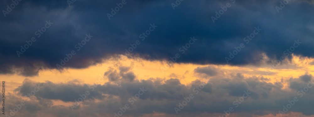 Dark storm clouds illuminated by the bright evening sun, panorama