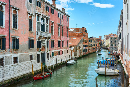 Beautiful view of canal in Venice, Italy, with boats on the water surrounded by old picturesque colorful houses under vivid blue sky on spring day. © Eduardo Accorinti