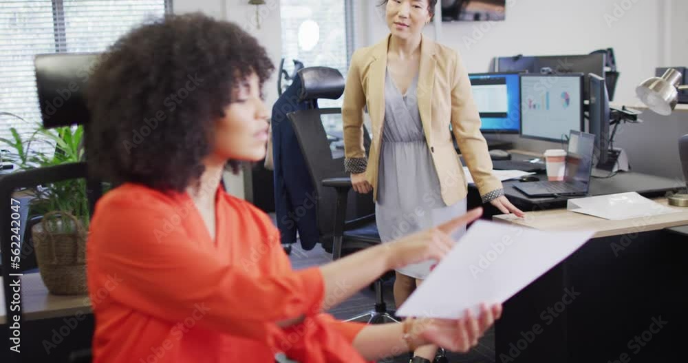 Diverse businesswomen talking and holding documents in office, slow motion Diverse businesswomen talking and holding documents in office, slow motion