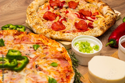 Two different pizza with ingredients on rustic background. Pepperoni pizza and pizza Capricciosa with mozzarella cheese, ham, tomato sauce, salami, mushroom, pepper, spices and fresh basil