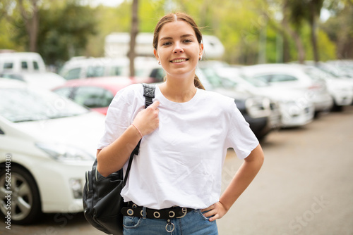 Portrait of a smiling confident girl standing in the parking lot near the cars photo