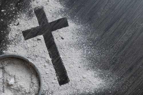 Bowl of ashes and cross of ashes on a dark wood background with copy space