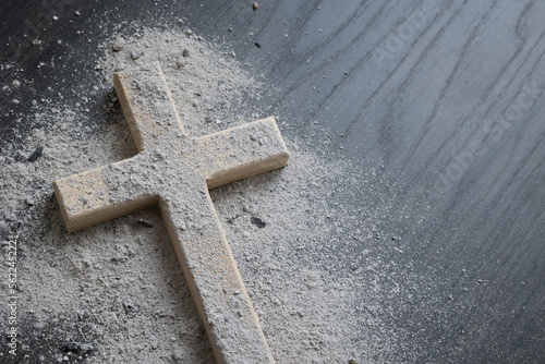 Wood cross covered with ashes on a dark wood background with copy space