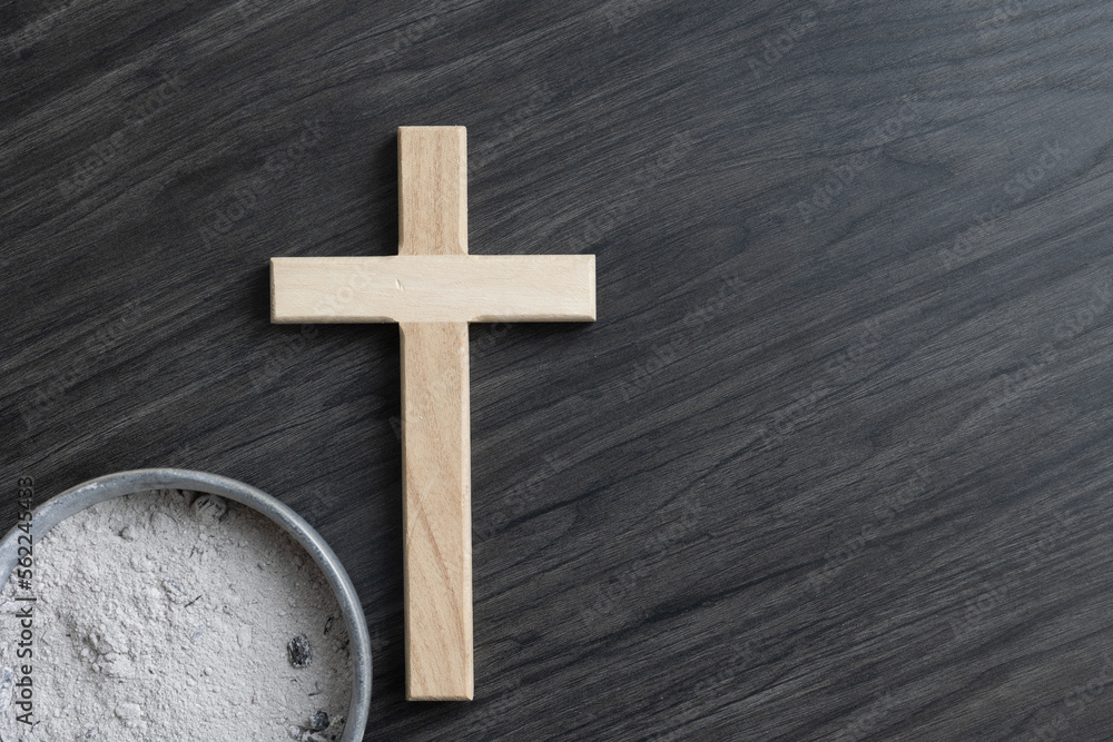 Wood cross and bowl of ashes on a dark wood background with copy space