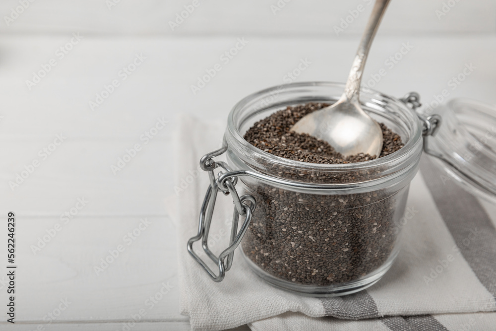 Chia seeds in a small glass jar and a spoon on a white wood background. SUPERFOOD and antioxidant. Healthy food concept. Gluten free. Chia seeds in a small glass jar and a spoon on a white wood background. SUPERFOOD and antioxidant. Healthy food concept. Gluten free.
