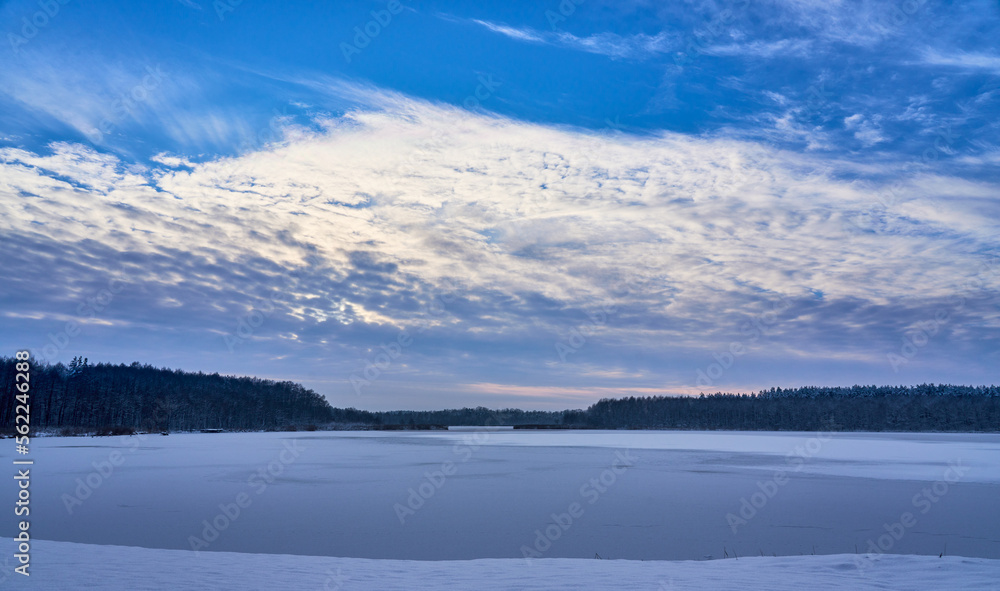 Frozen lake. Blue sky over frozen lake. Beautiful clouds over snow covered lake. Winter wonderland.