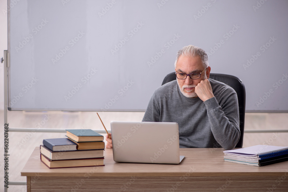 Old male teacher in the classroom Old male teacher in the classroom