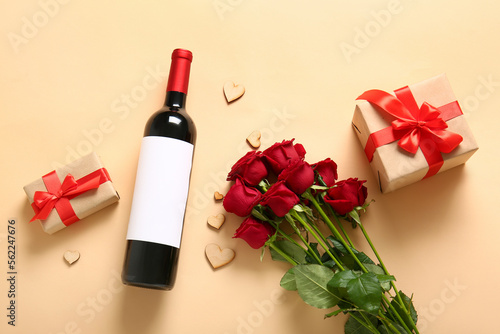 Bottle of wine, rose flowers, gifts and heart-shaped cookies on beige background. Valentine's Day celebration