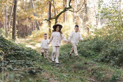 Happy childs are have rest and have fun in park in fresh air. Children run to the camera, outdoor activity in warm day. Sibling, little girl and two boys on green grass in the forest. Kid dream team. © Andriy Medvediuk