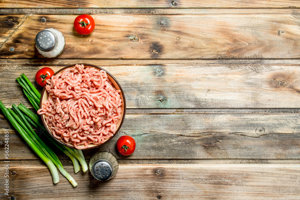 Raw minced beef in a bowl with tomatoes and green onions. Raw minced beef in a bowl with tomatoes and green onions.