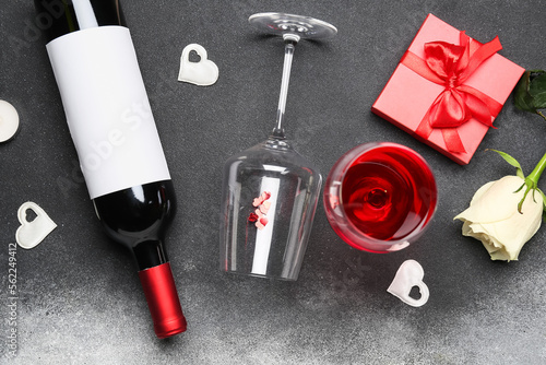 Bottle of wine, glass, hearts and gift box on black table. Valentine's Day celebration