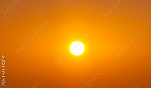 Sun shining on the clear orange sky at summer sunset