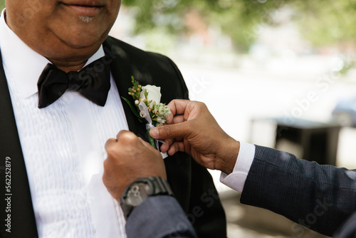 The hands straighten the boutonniere 
