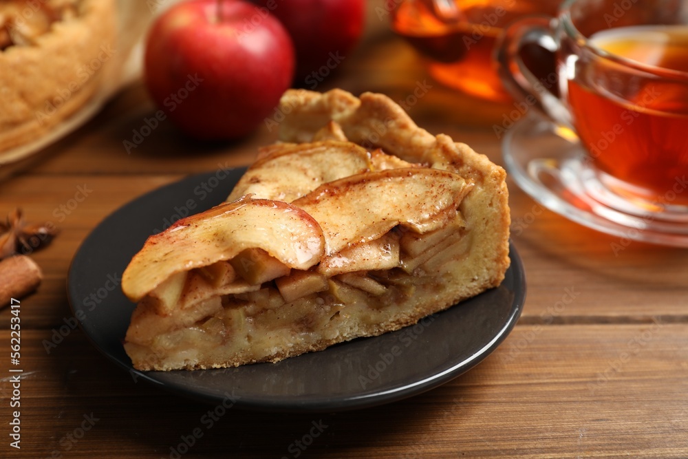 Slice of delicious apple pie served with tea on wooden table, closeup Slice of delicious apple pie served with tea on wooden table, closeup