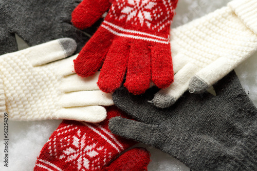 Warm gloves on a white background. Red and grey gloves. Snowy background. Close up.