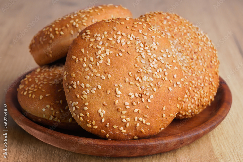 Fresh buns with sesame seeds on wooden table, closeup