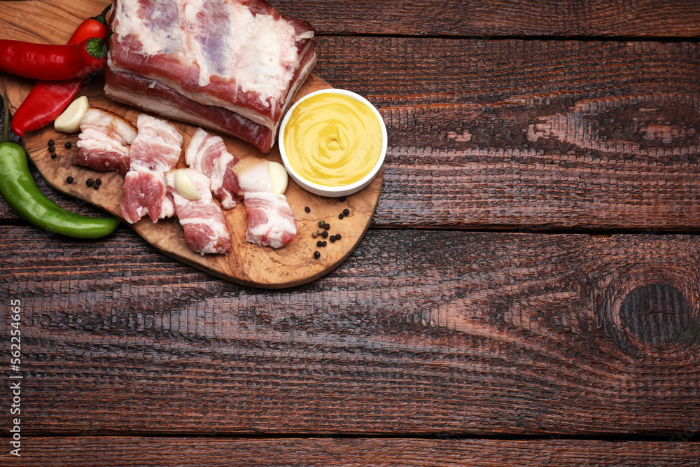 Pieces of pork fatback with chilli pepper and sauce on wooden table, top view. Space for text Pieces of pork fatback with chilli pepper and sauce on wooden table, top view. Space for text